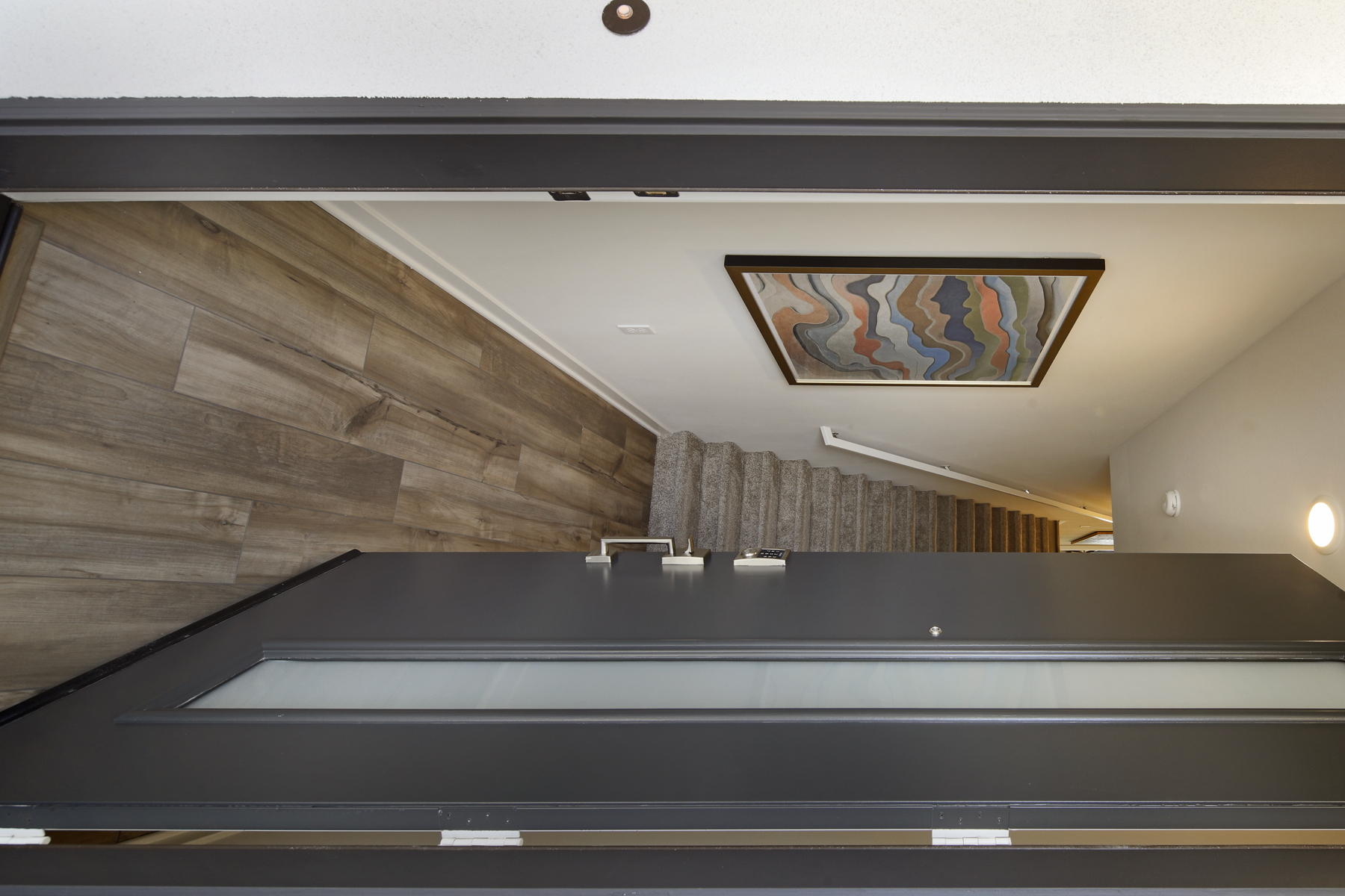 A hallway with a wood floor and a painting on the wall.