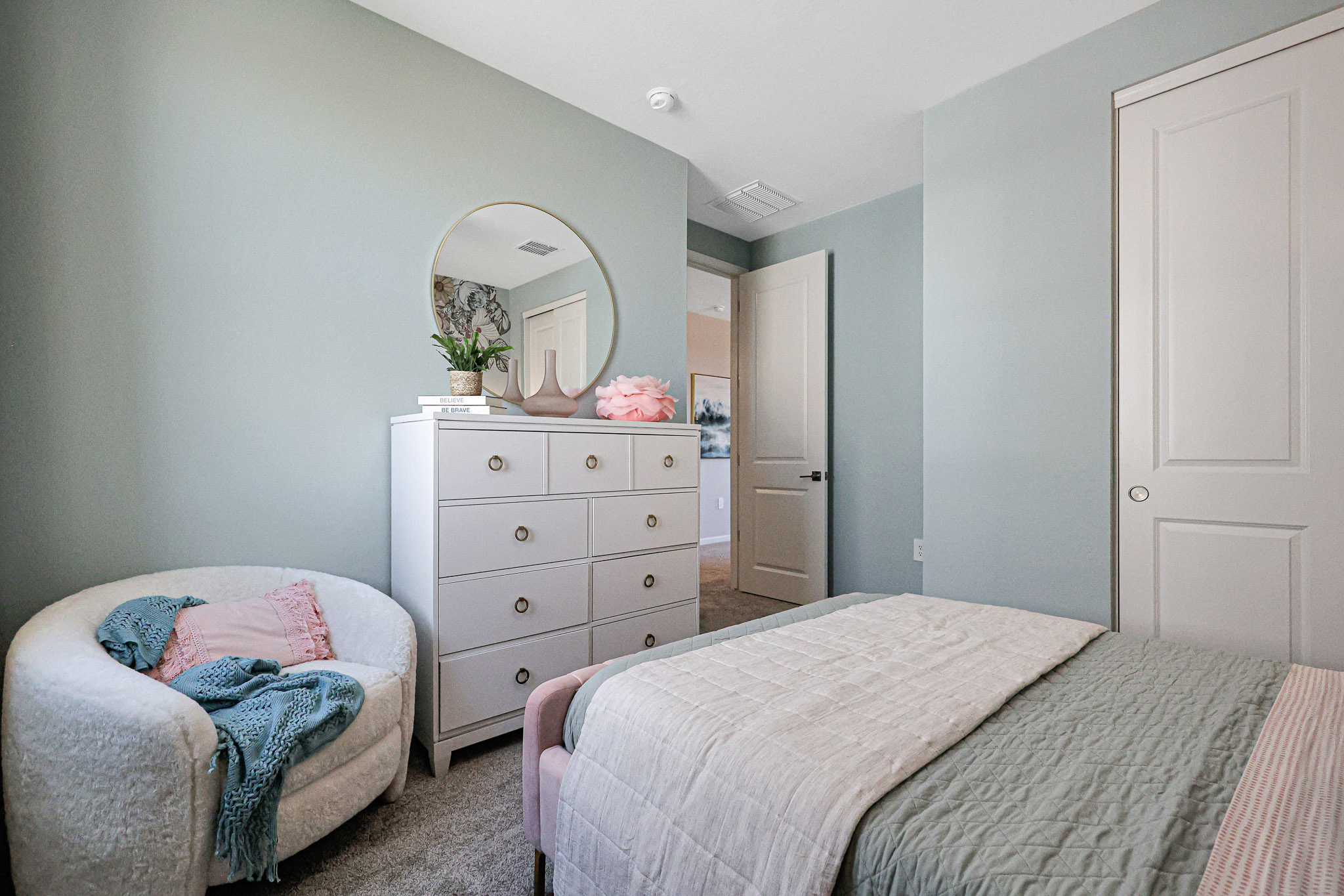 A bedroom with a mirror and a bed.