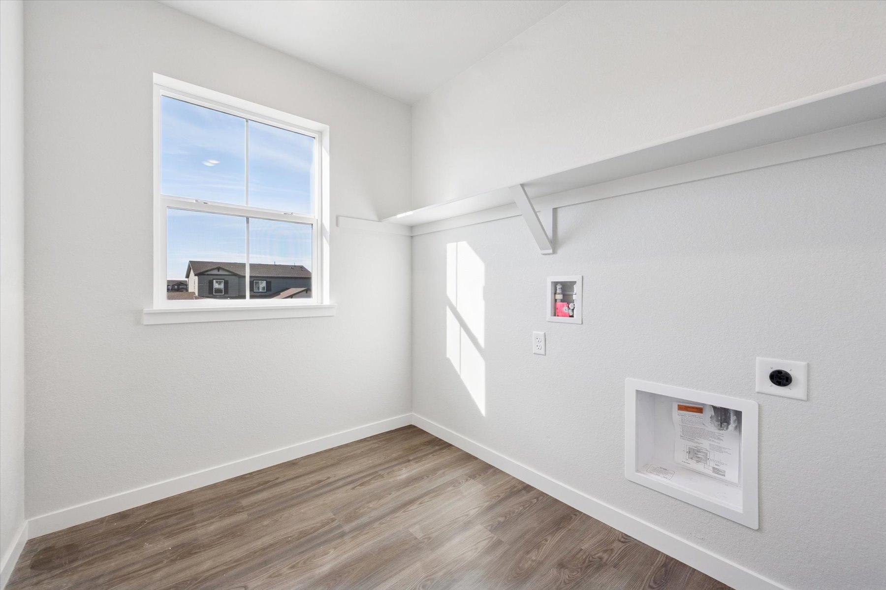A room with a wood floor and a window with a window.