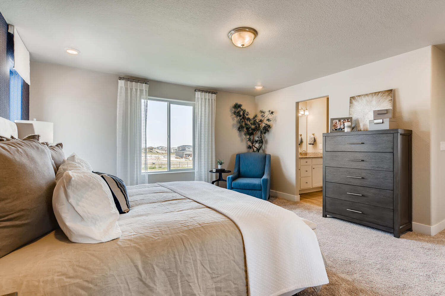 A bedroom with a bed and a chair.