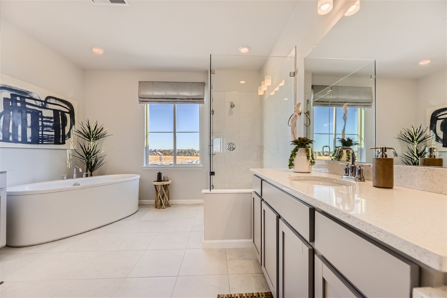 A bathroom with a tub sink and a large mirror.