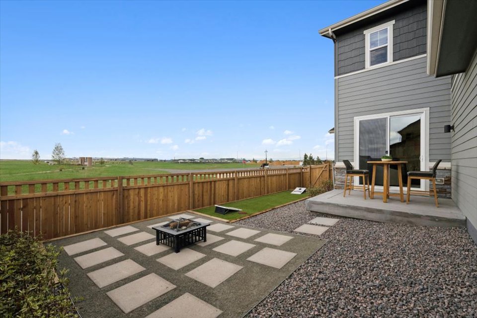 A backyard with a fence and a patio with a table and chairs.