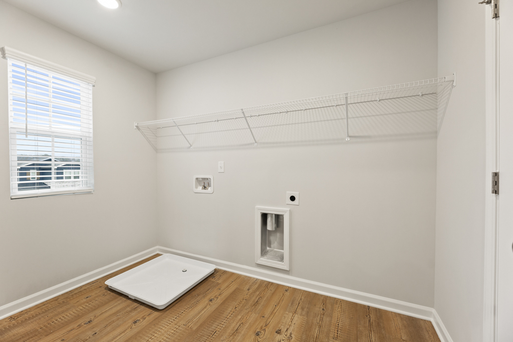 A room with a white wall and a wood floor.
