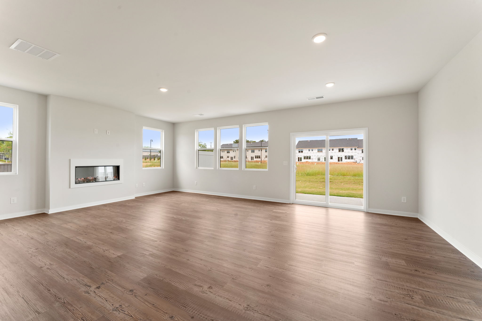 A large empty room with a wood floor and a large window.