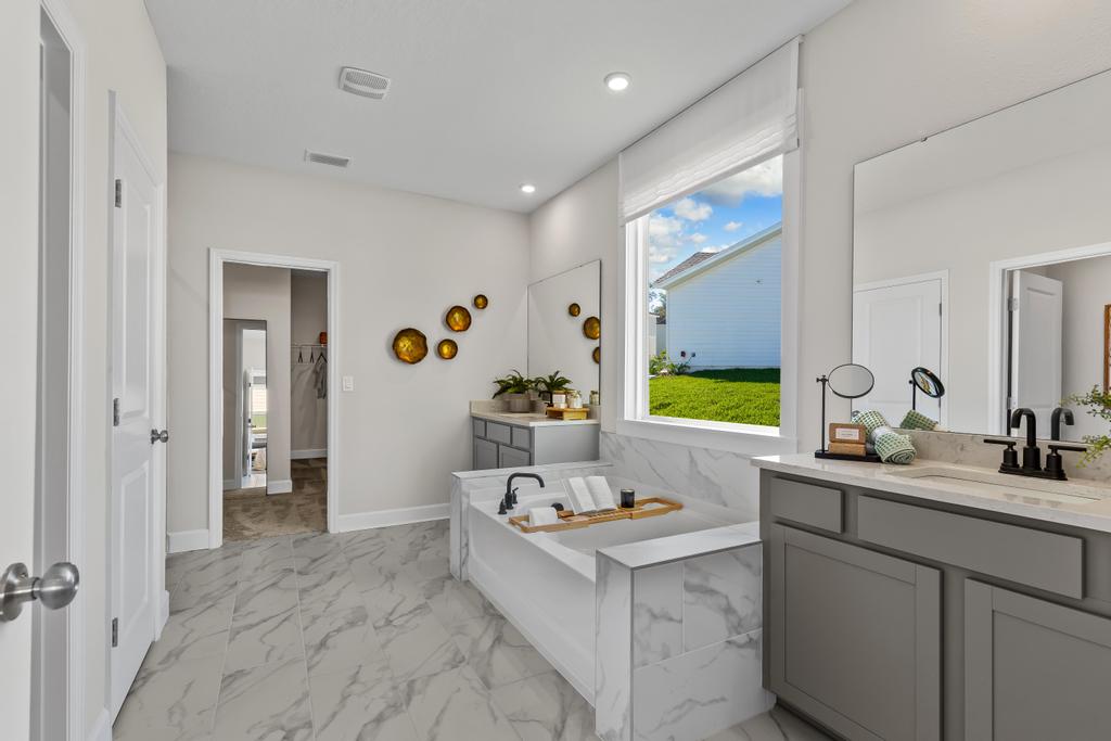 A bathroom with a tub sink and a large window.