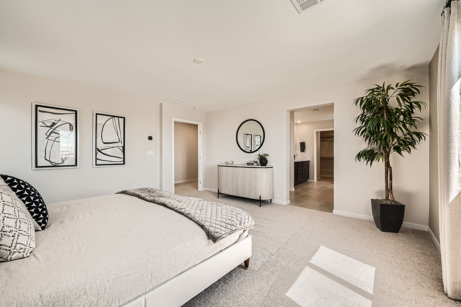 A bedroom with a bed and a plant.