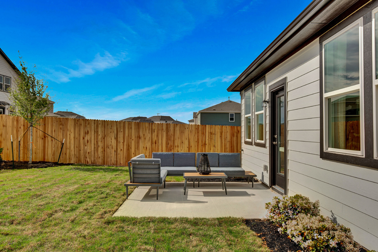 A backyard with a fence and a table and chairs.