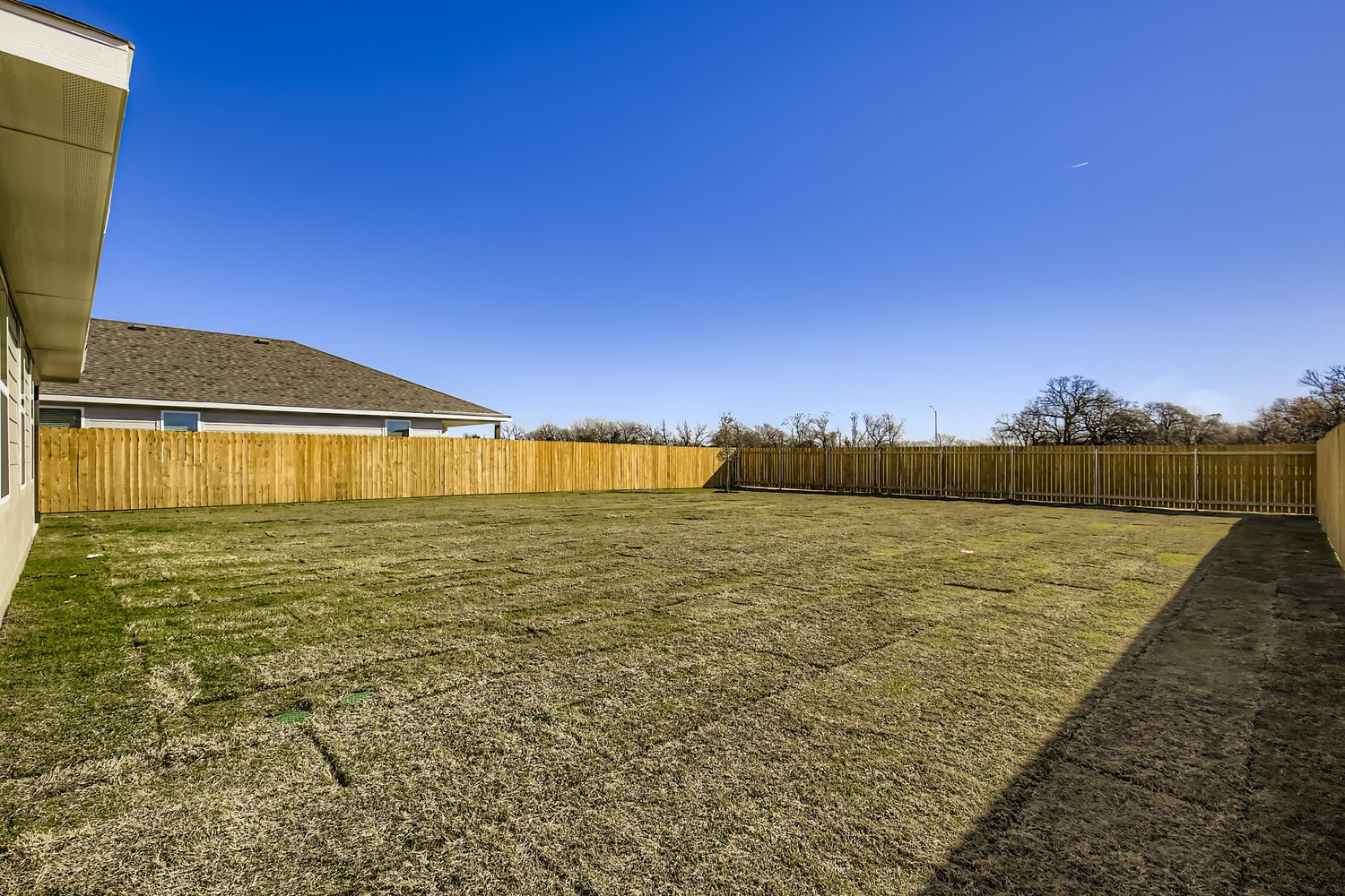 A fenced in yard with a house and trees in the background.