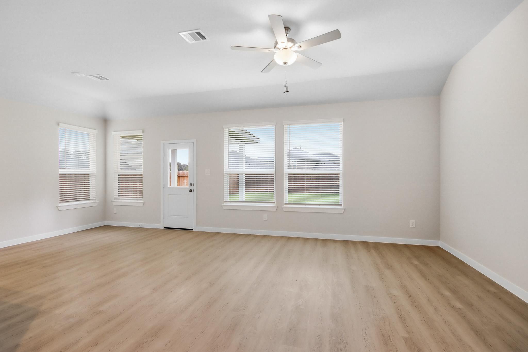 A room with a ceiling fan and a wood floor.