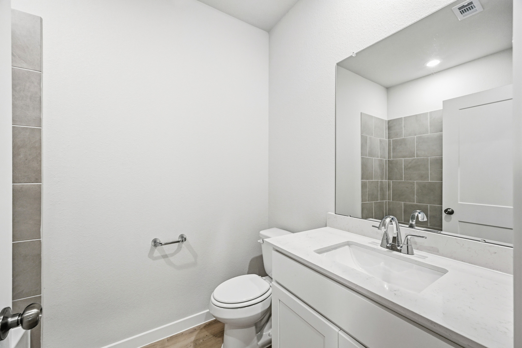 A bathroom with a sink toilet and mirror.