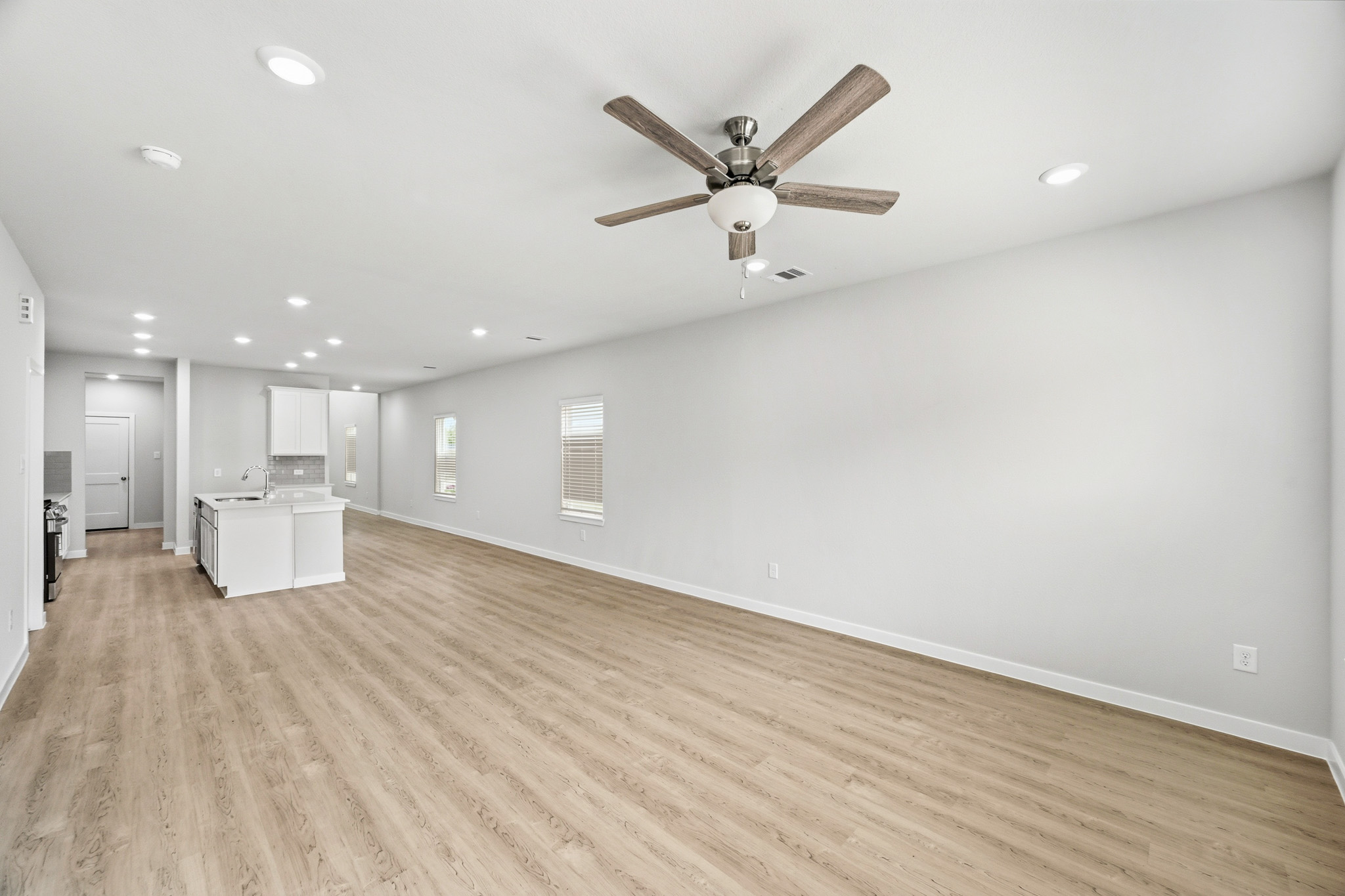 A large empty room with a ceiling fan and a wood floor.