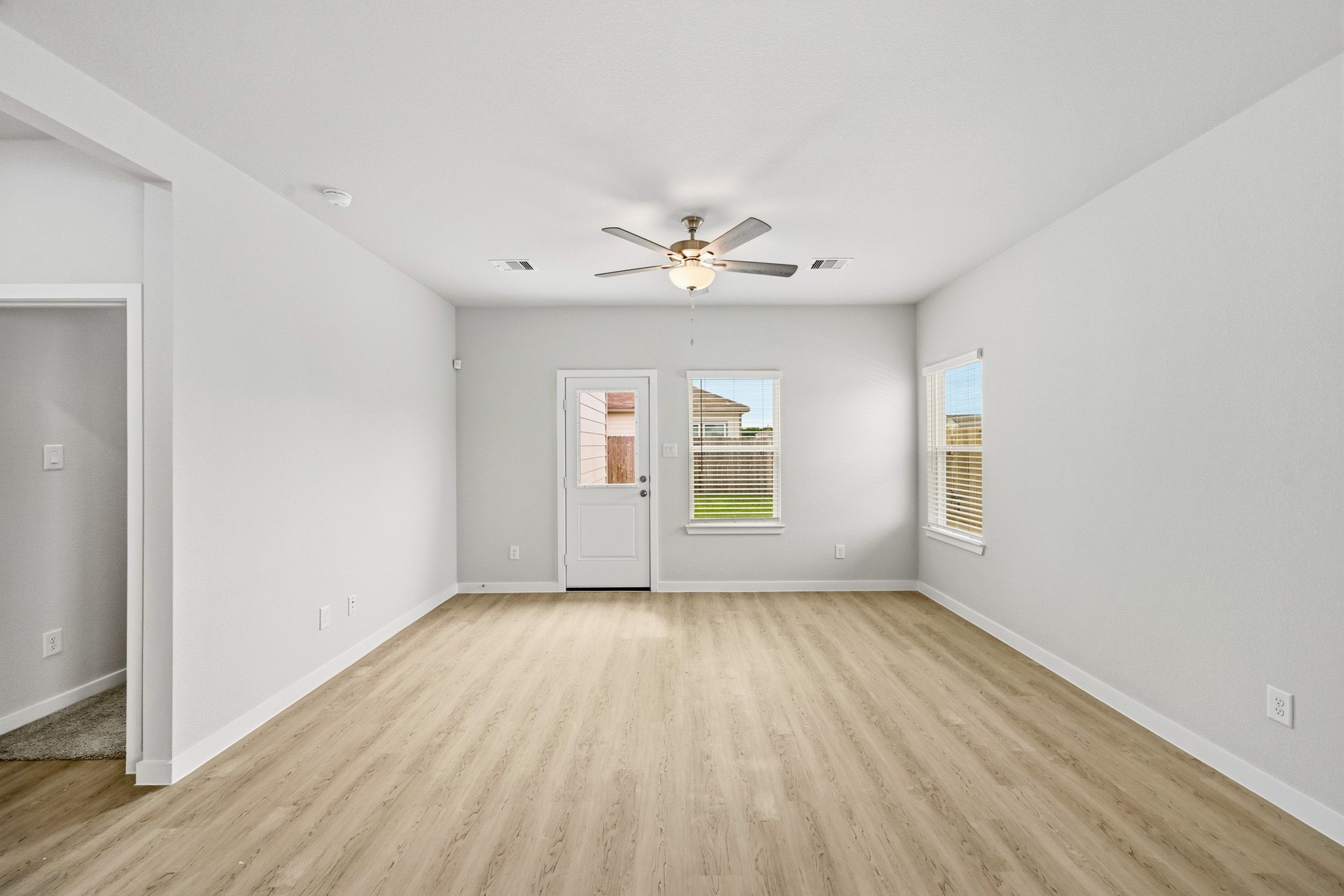 A room with a ceiling fan and a wood floor.