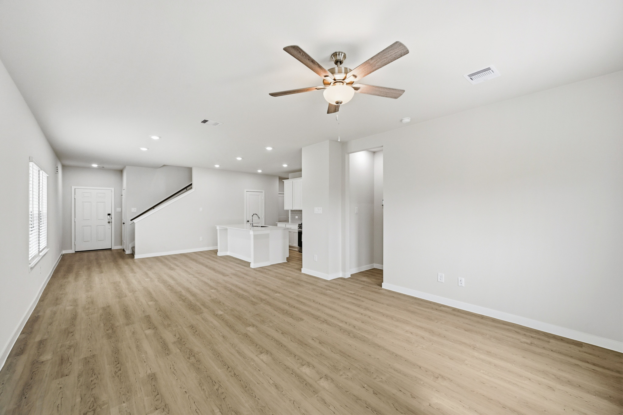 A large empty room with a ceiling fan and a wood floor.