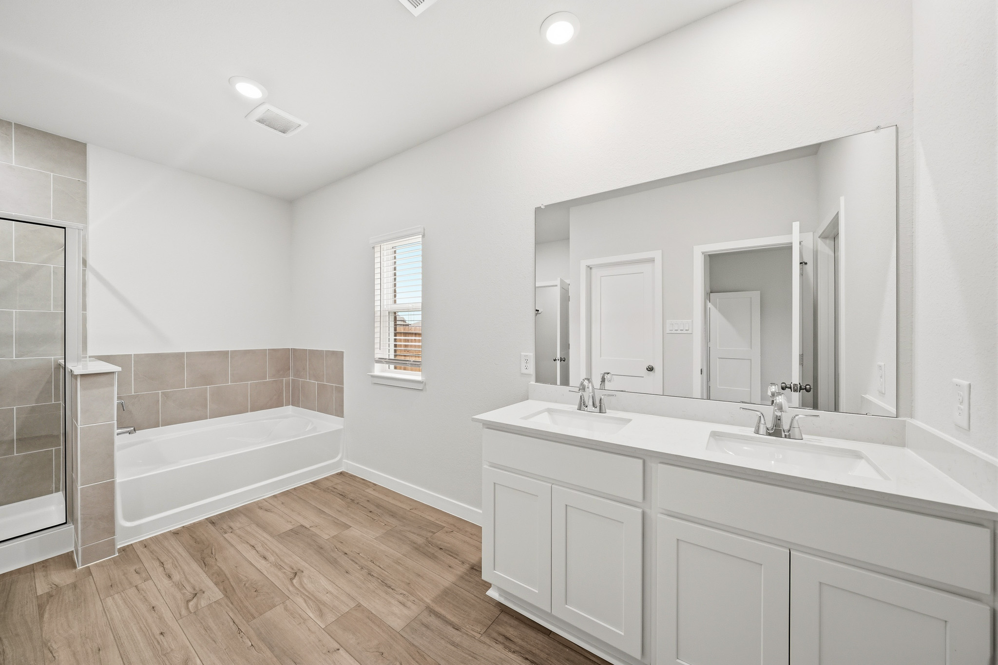 A bathroom with a tub sink and a mirror.