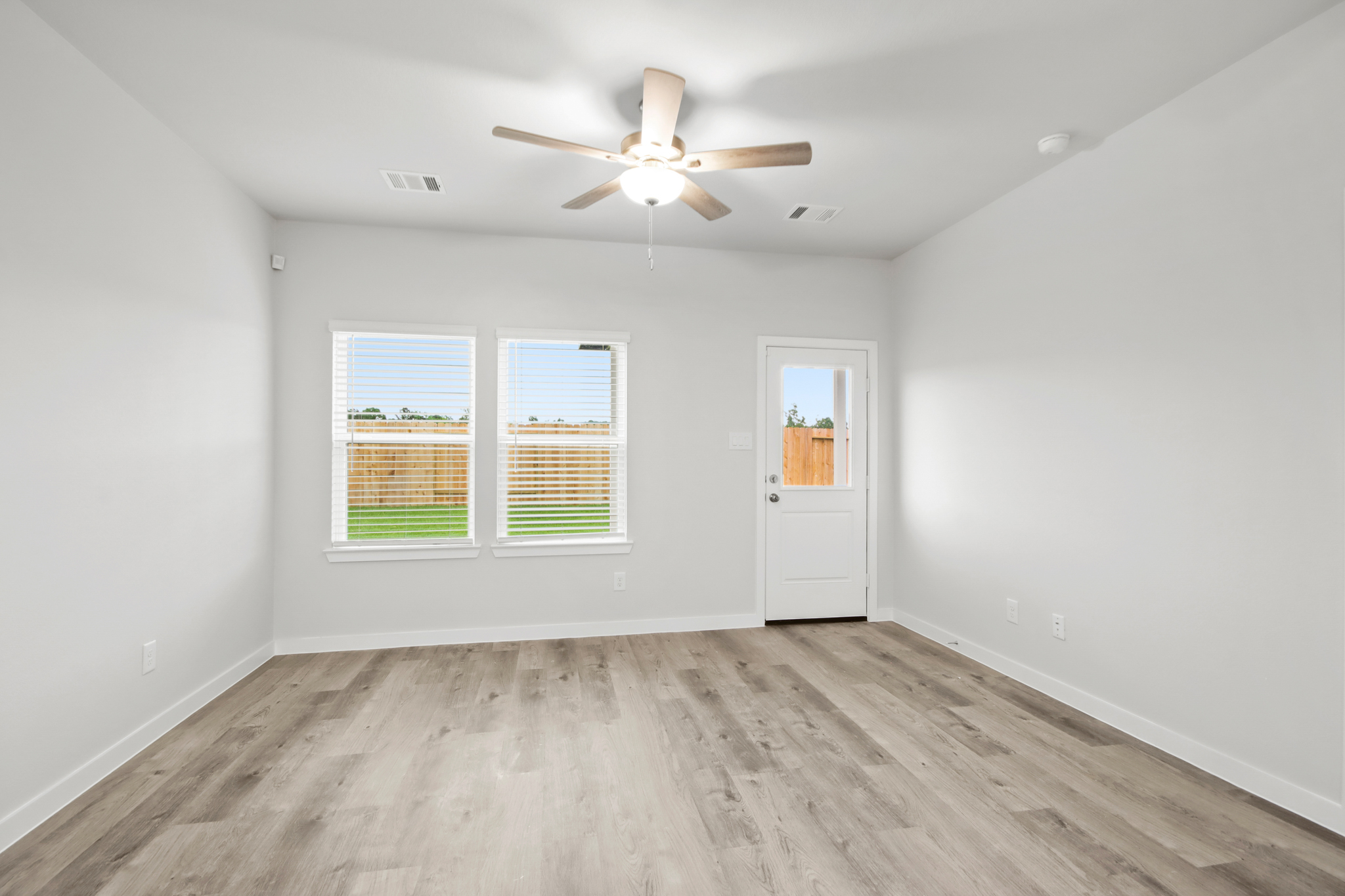 A room with a ceiling fan and a wood floor.