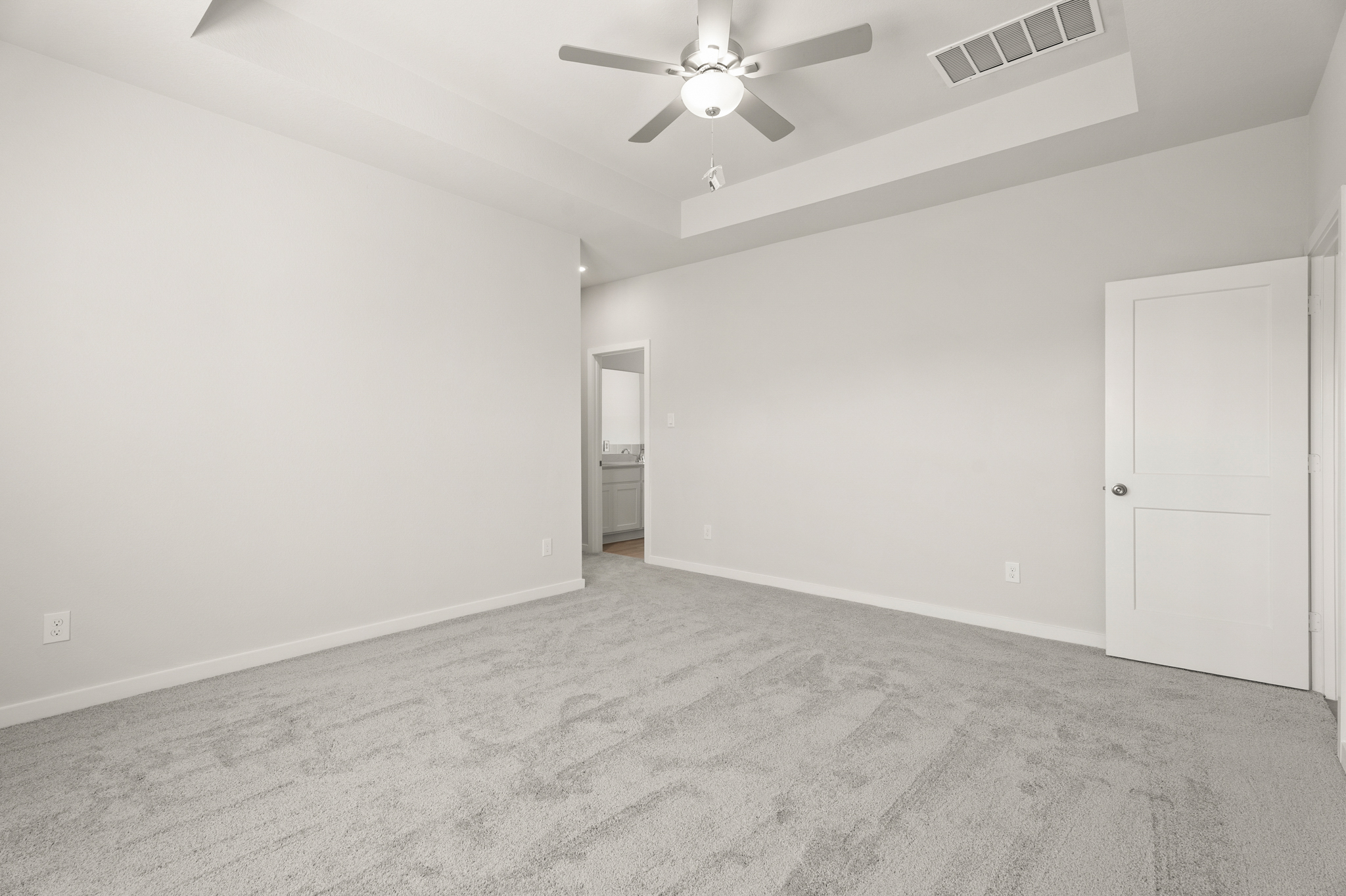 A room with a ceiling fan and a door.