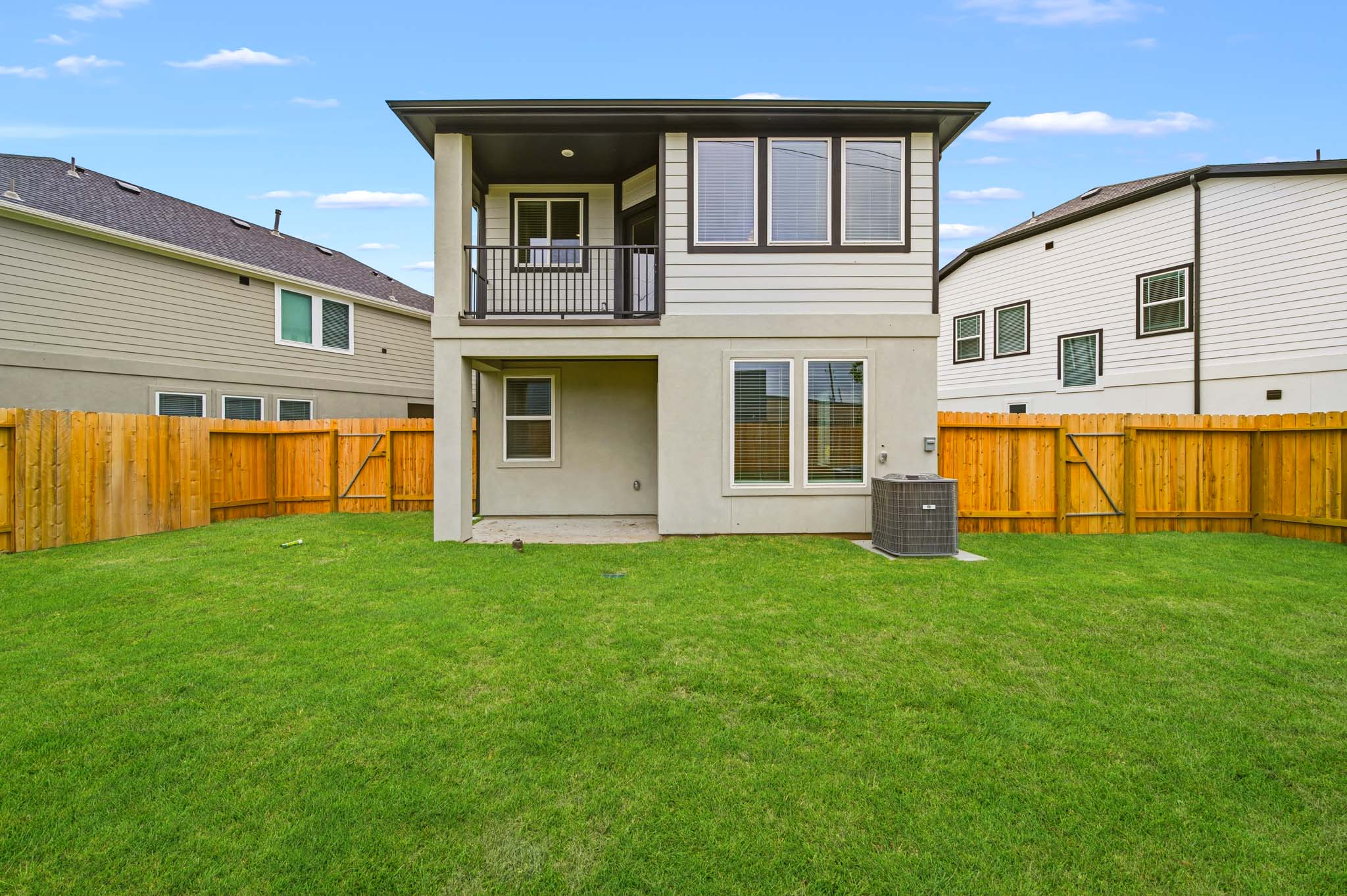 A house with a fence and a lawn in front of it.
