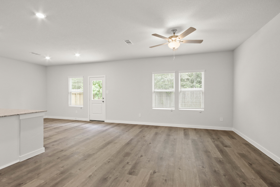 A room with a ceiling fan and a wood floor.