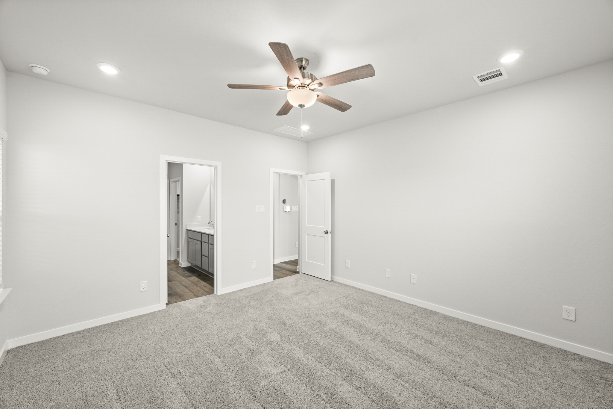 A room with a ceiling fan and a carpet.
