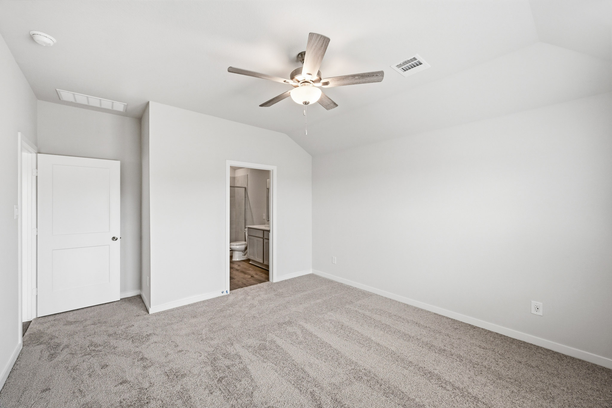 A room with a ceiling fan and a carpet.