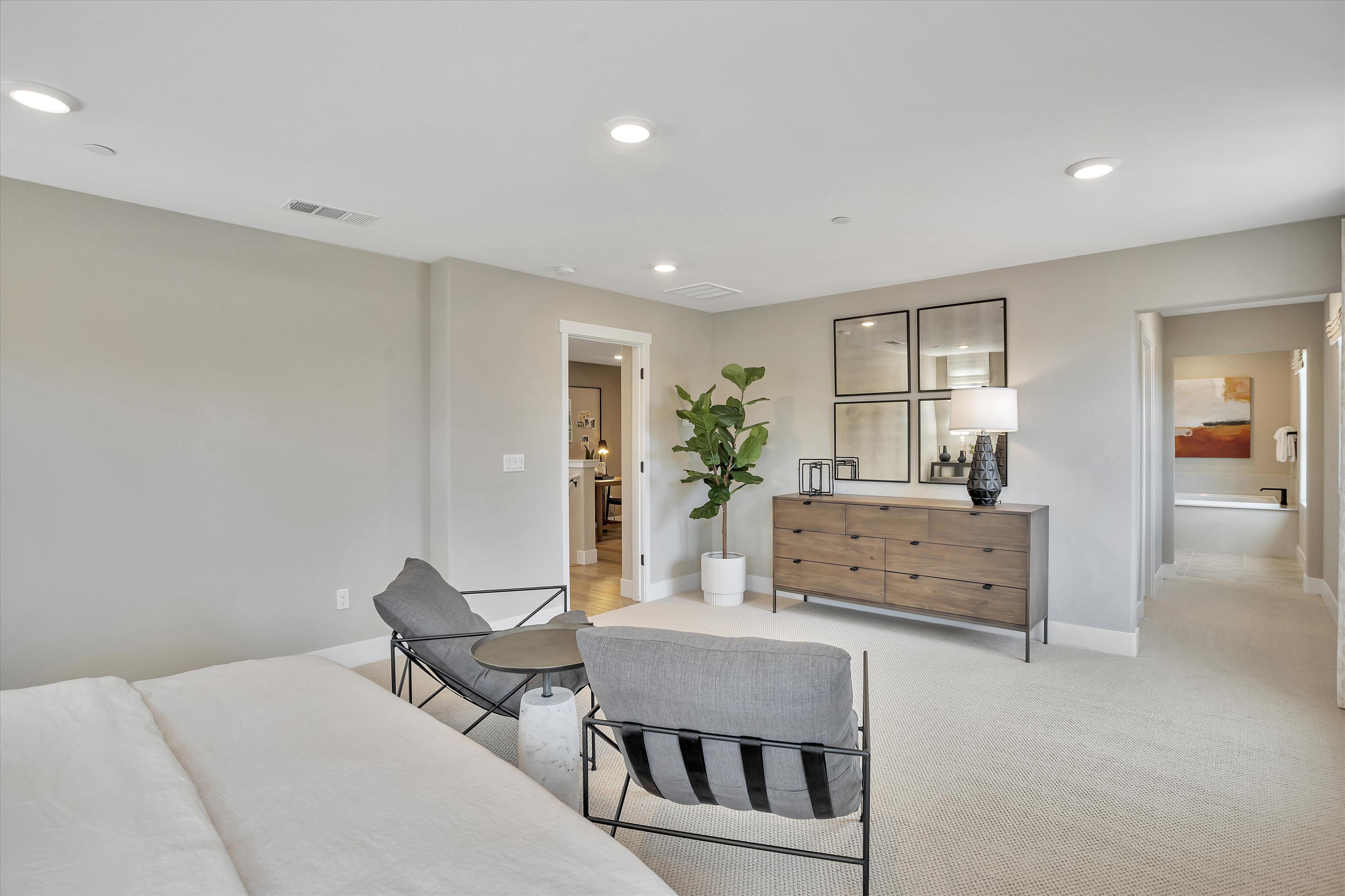 A room with a bed and chairs.