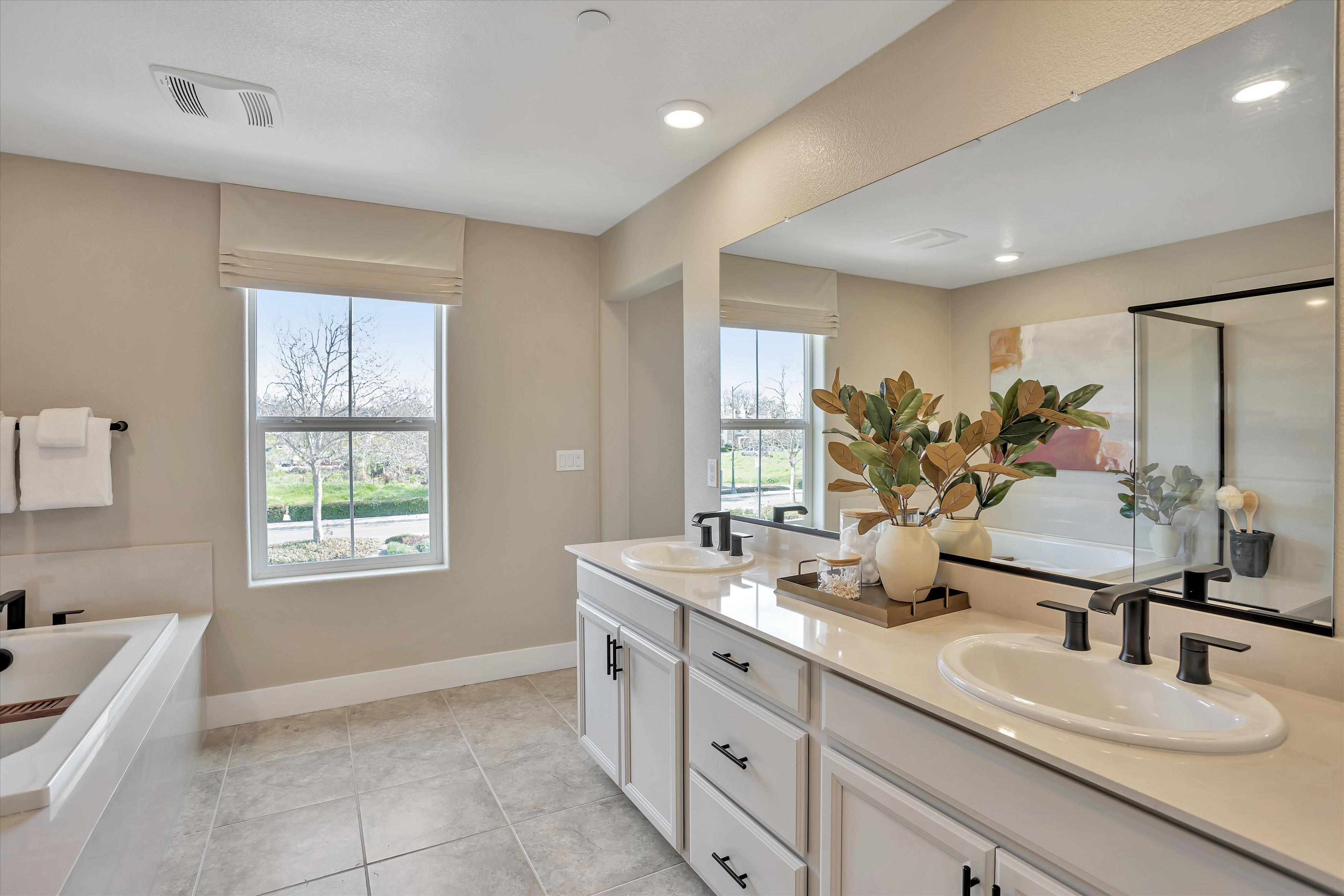 A bathroom with a tub sink and a large mirror.